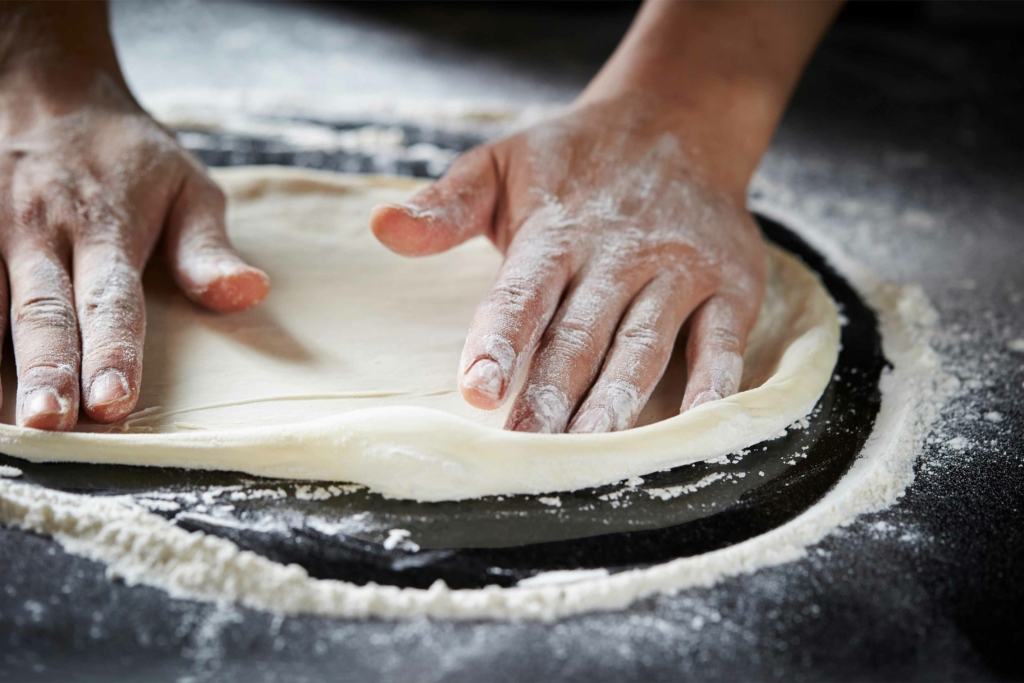 mani di donna che impastano una pizza