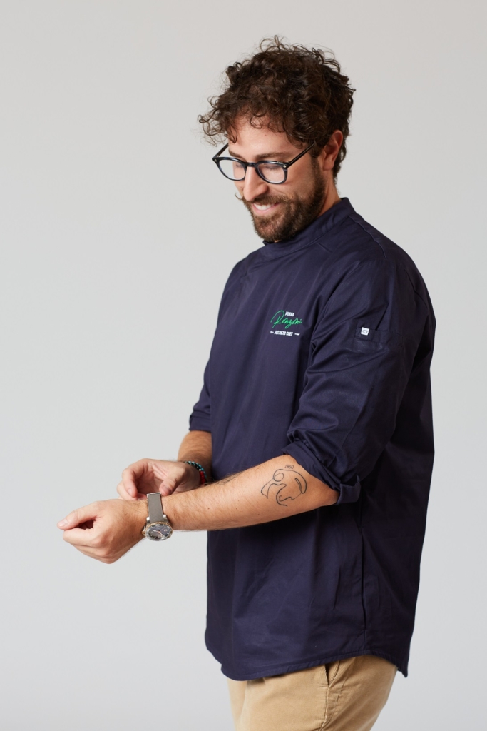 Mirko Ronzoni con giacca da chef che si sistema l'orologio al polso