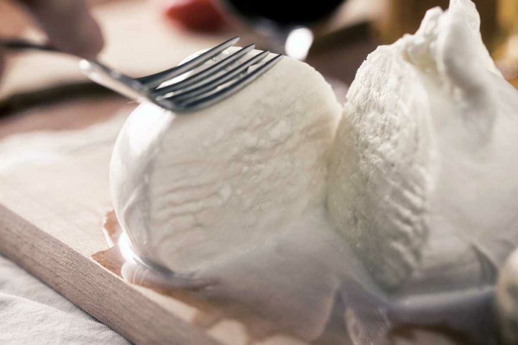 Mozzarella con forchetta che la schiaccia per fa fuoriuscire la lacrima