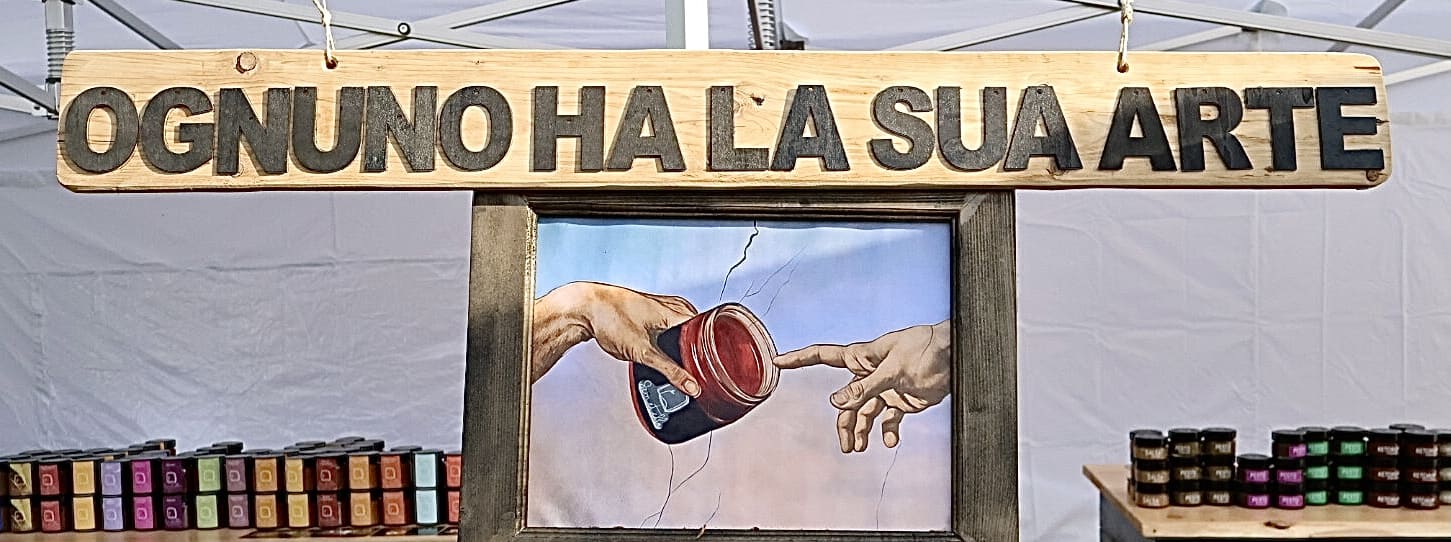 Pannello di legno con lo slogan originale dell'azienda Semetella, appeso nel loro stand, che mira a valorizzare il loro lavoro e il loro prodotto di nicchia: le conserve di frutta